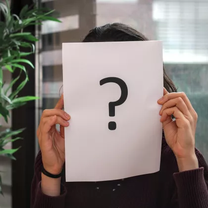 a picture of a person holding a sheet of paper with a question mark in front of their face